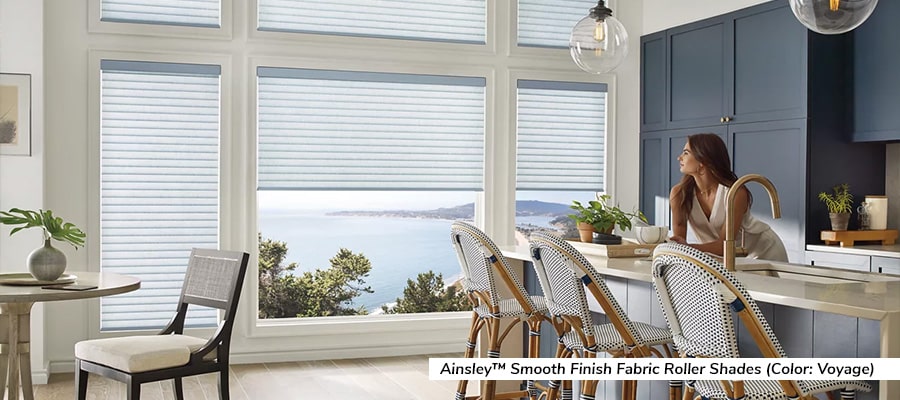Partially drawn shades let a female homeowner enjoy the morning light in her modern kitchen.