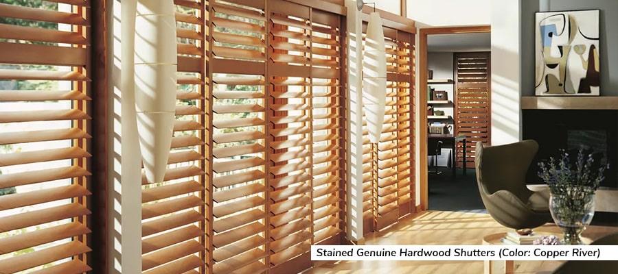 Wooden shutters over tall windows filter light into modern living room.