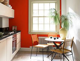 Interior image of a small kitchen with red and white walls and dining furniture set.